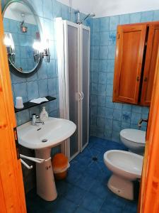 bagno piastrellato blu con lavandino e servizi igienici di Appartamento La Foresta Abetone ad Abetone
