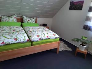 a bedroom with a bed with green sheets and a plant at Haus Am Waldesrand in Fichtelberg