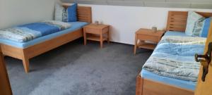 - une chambre avec 2 lits et 2 tables de chevet dans l'établissement Haus Am Waldesrand, à Fichtelberg