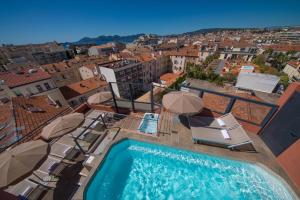 a pool with chairs and umbrellas on top of a building at Eden Hotel & Spa in Cannes