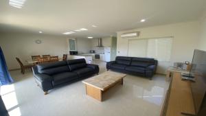 ein Wohnzimmer mit zwei schwarzen Sofas und einem Tisch in der Unterkunft Unit 46 Seafront Estate in Jurien Bay