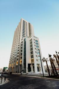 a tall white building with palm trees in front of it at Abdali Views Apartments in Amman