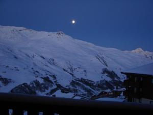 uma lua a erguer-se sobre uma montanha coberta de neve à noite em Necou 721 em Les Menuires