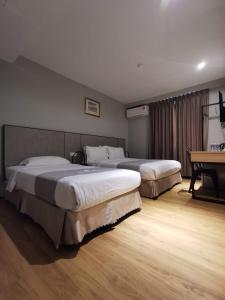a bedroom with two beds and a table and a desk at OCEAN HOTEL in Labuan