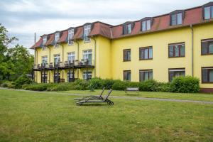 ein großes gelbes Gebäude mit einer Bank im Gras in der Unterkunft Seehotel Brandenburg an der Havel in Brielow