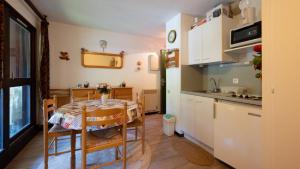 cocina con mesa y cocina pequeña con armarios blancos en Le Grand Neige - 36 - Appart Montagne 6 pers en Morillon