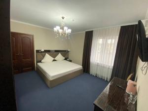 1 dormitorio con cama blanca y lámpara de araña en Comfortplace en Atyraū
