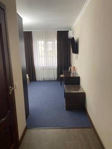 Una habitación de hotel con un escritorio y una ventana. en Comfortplace, en Atyraū