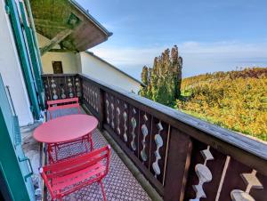 a balcony with two red chairs and a table at Domaine de la Crausaz in Grandvaux