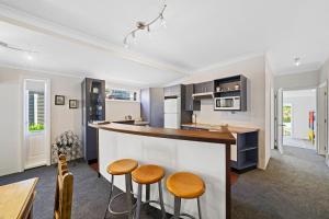 - une cuisine avec un comptoir et des tabourets dans une pièce dans l'établissement Te Kawa Cottage - Martinborough Holiday Home, à Martinborough