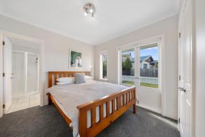 - une chambre avec un grand lit et une fenêtre dans l'établissement Te Kawa Cottage - Martinborough Holiday Home, à Martinborough