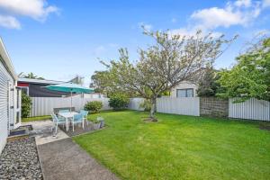 une arrière-cour avec une table et un arbre dans l'établissement Te Kawa Cottage - Martinborough Holiday Home, à Martinborough