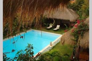 a swimming pool in a resort with a straw roof at KUTA - 4BR Villa with Private XL Pool in Kuta