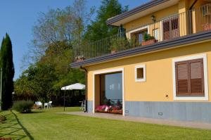 a yellow house with a balcony and a yard at L'Infinito Agriturismo - Rooms & Breakfast in SantʼAlfio