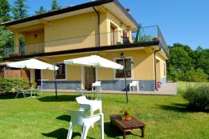 a house with white chairs and tables and umbrellas at L'Infinito Agriturismo - Rooms & Breakfast in SantʼAlfio