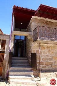 a stone building with stairs and a balcony at Casa dos Ferros 
