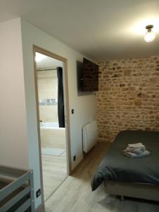 a bedroom with a bed and a brick wall at La poule aux oeufs dort in Soudan