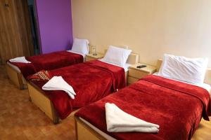 Cette chambre comprend 3 lits avec des draps rouges et des serviettes blanches. dans l'établissement Dweik Hotel 1, à Aqaba