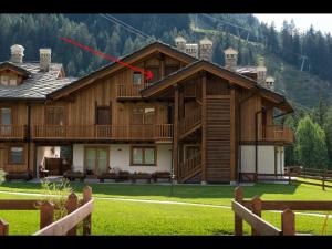 a large wooden house with a red arrow on it at Appartamento Jardin des Alpes. in La Thuile