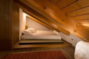 a bed in the middle of a room with wooden ceilings at Appartamento Jardin des Alpes. in La Thuile