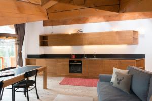 a kitchen with wooden cabinets and a table and a couch at Appartamento Jardin des Alpes. in La Thuile