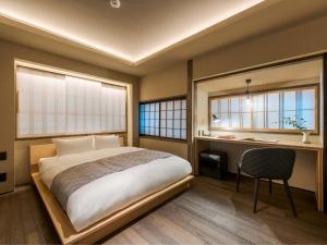 a bedroom with a bed and a desk and two windows at Kanata Machiya House in Kanazawa