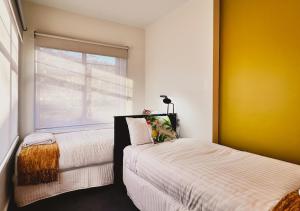 - une chambre avec 2 lits et une fenêtre dans l'établissement Hobart Rose Court Apartments "Avitium", à New Town
