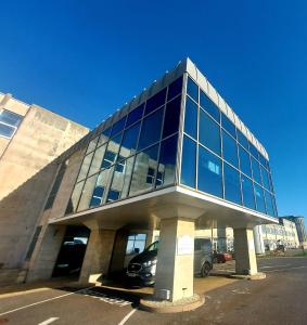 a large glass building with a car parked in front at The New Admiralty Hotel Ltd in Portland