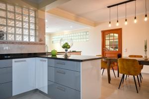 a kitchen with white cabinets and a dining table at Villa Mendonca, a Home in Madeira in Canhas
