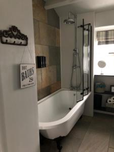 a bath tub in a bathroom with a sign on the wall at Mistletoe Cottage in Foulridge