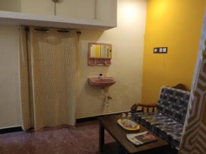 baño con lavabo, sofá y mesa en NKS Homestay, en Pondicherry