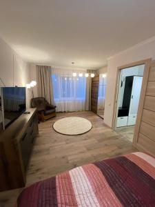 um quarto com uma cama e uma televisão e uma sala de estar em Прелестное жильё у Akropole, бесплатная парковка. em Riga