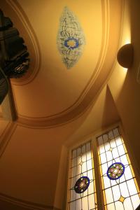 a ceiling with a chandelier and stained glass window at Albergo Alla Posta in Trieste