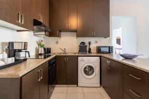 a kitchen with wooden cabinets and a washer and dryer at Araminta 2-Bedroom Apartment in Larnaca in Larnaka +12 photos