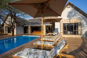 a pool with two lounge chairs and an umbrella at Vuyani Marula Lodge in Hoedspruit