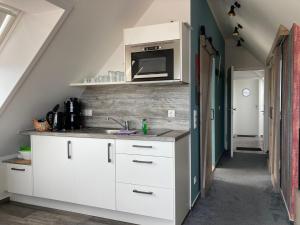 eine Küche mit weißen Schränken und einer Mikrowelle in der Unterkunft Urban Nature13 in Grömitz