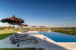 a swimming pool with two picnic tables and an umbrella at Villa Aga - Homelike Villas in Cingoli