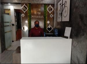 um homem usando uma máscara de rosto em pé em um quarto em Hotel Riya Imperial By WB Inn em Gondia