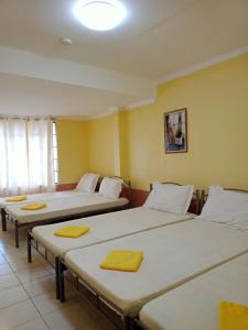 3 camas en una habitación con paredes amarillas en La Vista Pansol Resort Complex by RedDoorz, en Pansol
