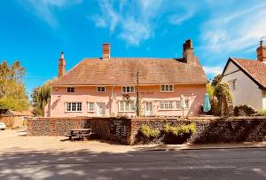 a large pink house with a bench in front of it at Outdoor Inns - Star at Lidgate in Newmarket