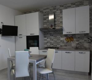 een keuken met witte kasten en een tafel en stoelen bij Sognando nel borgo in Rocca Imperiale