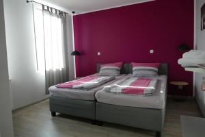 1 Schlafzimmer mit 2 Betten und einer lila Wand in der Unterkunft Pension Sölde in Dortmund
