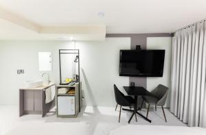 a living room with a tv and a table and chairs at HOTEL LENITH Seomyeon in Busan