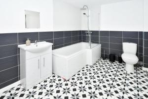 a bathroom with a toilet and a tub and a sink at Hanford Apartments in Stoke on Trent