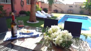 un tavolo di vetro con una bottiglia di vino e una ciotola di cibo di LOS CLAVELES a Hornachuelos