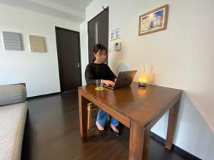 a woman sitting at a table with a laptop at サンコート南6条壱番館 in Sapporo