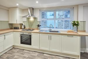 a kitchen with white cabinets and a sink and a window at Host & Stay - Sion Hall Cottage in Alnwick +10 photos