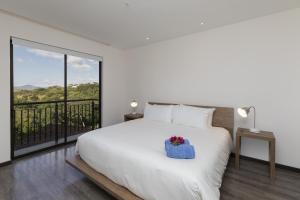 Un dormitorio con una cama blanca con una caja azul. en Roble Sabana 202 Luxury Apartment - Reserva Conchal, en Playa Conchal