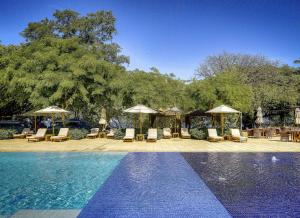 - une piscine avec des chaises longues et des parasols à côté dans l'établissement Roble Sabana 202 Luxury Apartment - Reserva Conchal, à Playa Conchal