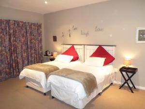 a bedroom with two beds with red pillows at Guest house Woodridge Forest 11 in Balgowan